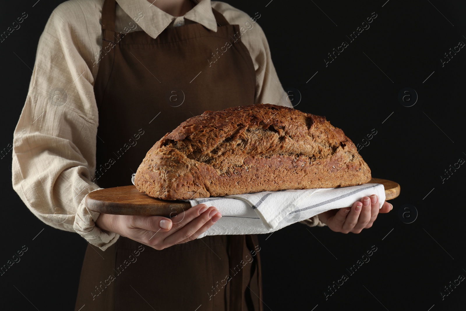 Photo of Woman holding freshly baked bread on black background, closeup