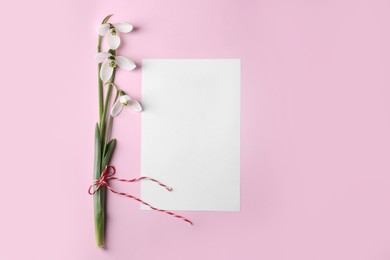 Beautiful snowdrops and paper card on pink background, flat lay. Space for text