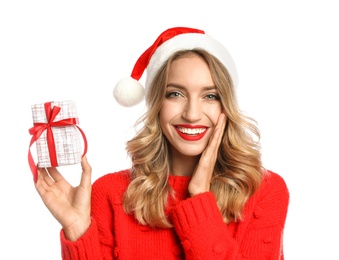 Happy young woman wearing Santa hat with Christmas gift on white background