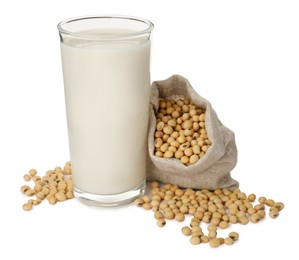 Photo of Glass of fresh soy milk and sack bag with beans on white background