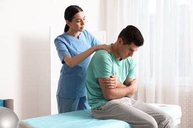 Orthopedist massaging man's back in clinic. Scoliosis treatment