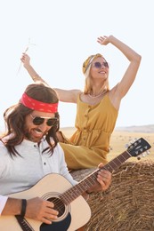 Photo of Beautiful hippie woman listening to her friend playing guitar in field