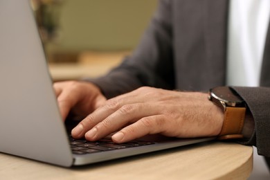 Photo of Man working on laptop at table in cafe, closeup