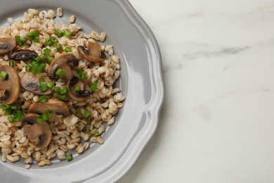 Photo of Delicious pearl barley with onion and mushrooms on white marble table, top view. Space for text