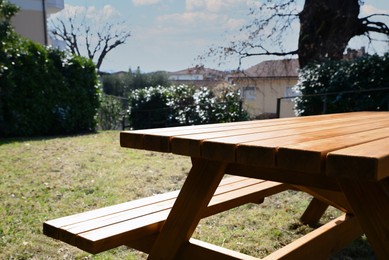 Photo of Empty wooden picnic table with bench in backyard on sunny day