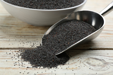 Poppy seeds in metal scoop on white wooden table