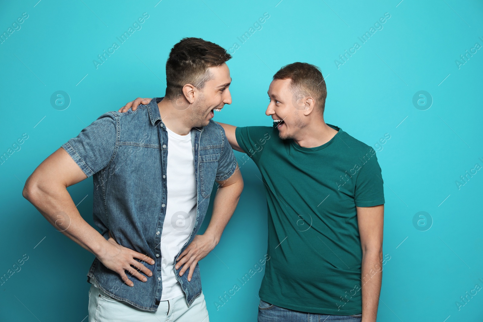 Photo of Man laughing with his friend against color background