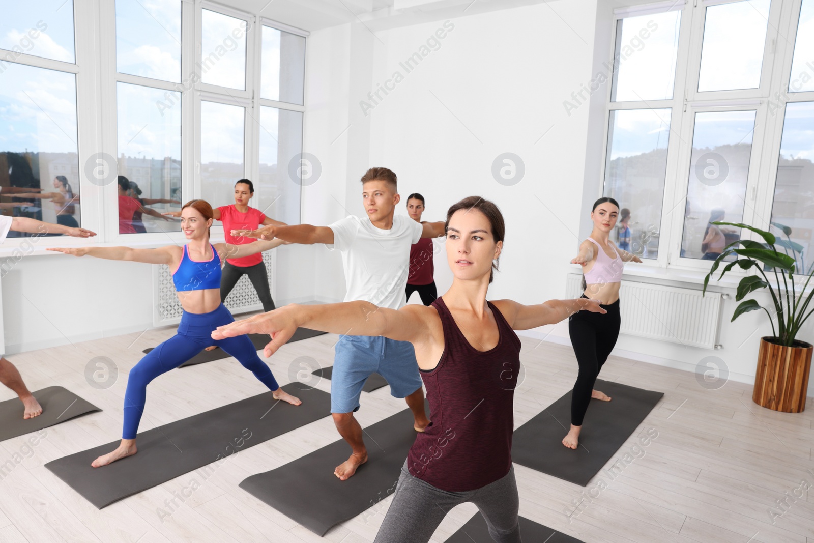 Photo of Group of people practicing yoga on mats indoors