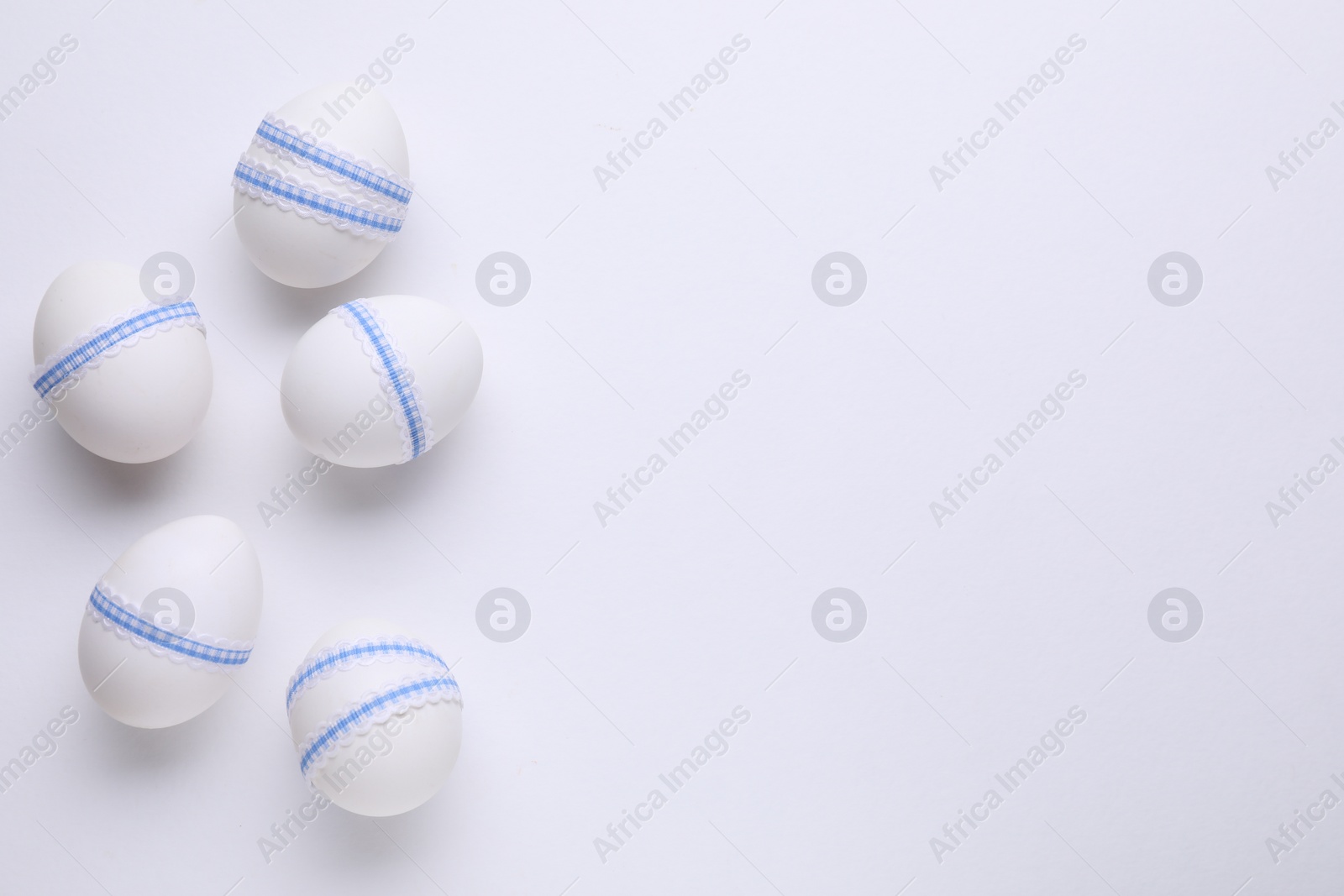 Photo of Festively decorated Easter eggs on white background, flat lay. Space for text