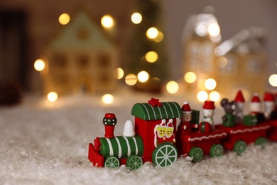 Photo of Bright toy train on artificial snow. Christmas atmosphere