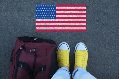 Image of Immigration. Woman with bag standing on asphalt near flag of USA, top view