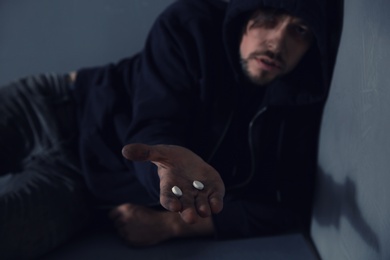Photo of Young addicted man holding drugs, focus on hand