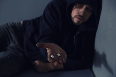 Young addicted man holding drugs, focus on hand