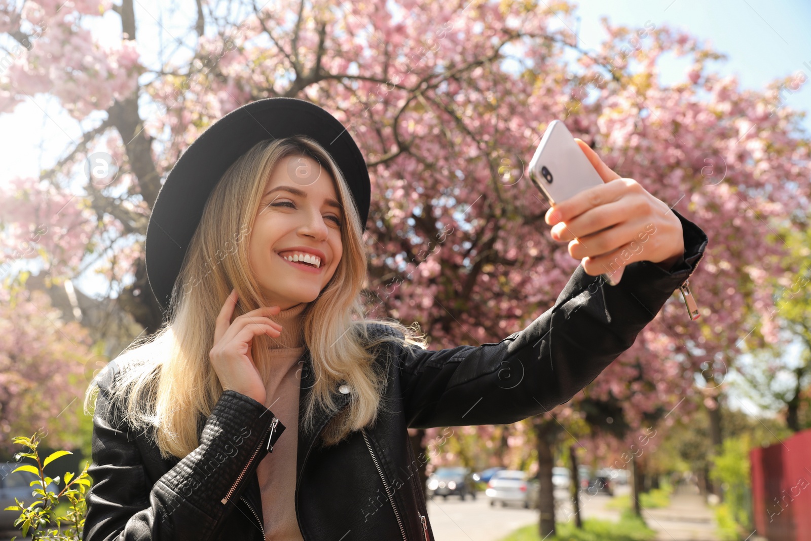 Photo of Happy woman taking selfie outdoors on spring day