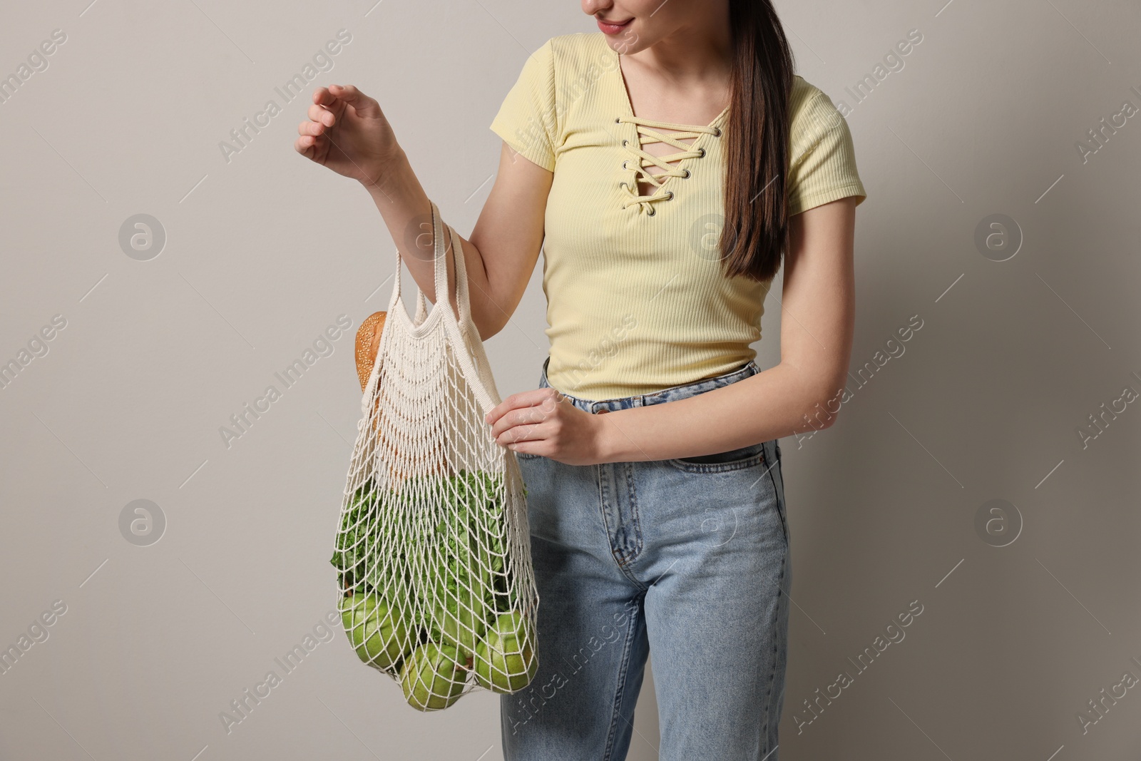 Photo of Woman with eco bag full of products on light background