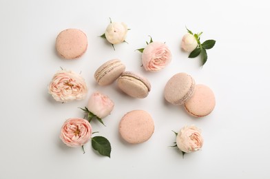 Flat lay composition with pink macarons and roses on white background