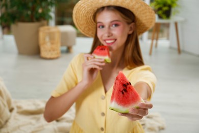 Photo of Beautiful teenage girl with slices of watermelon at home, focus on hand
