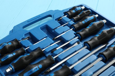 Set of screwdrivers in open toolbox on light blue wooden table, closeup