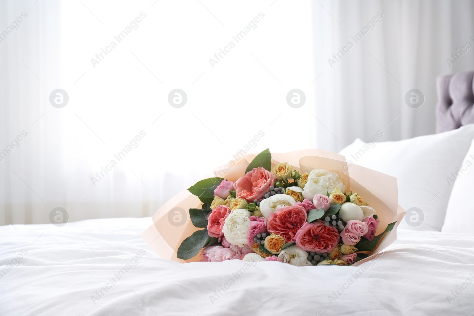 Photo of Beautiful flower bouquet on bed in light room. Space for text