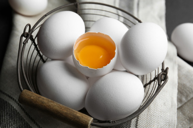 Photo of Chicken eggs in metal basket on table, closeup