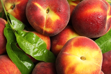 Tasty fresh peaches and leaves as background, top view