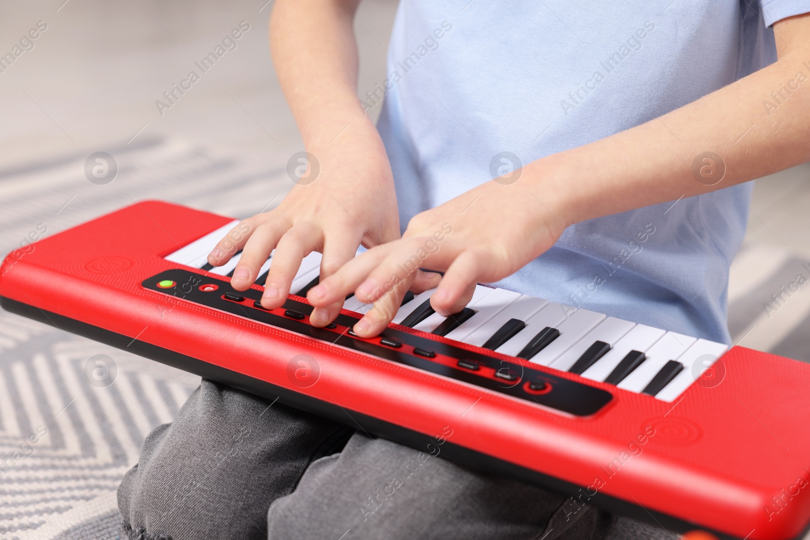 Photo of Little boy playing toy piano at home, closeup