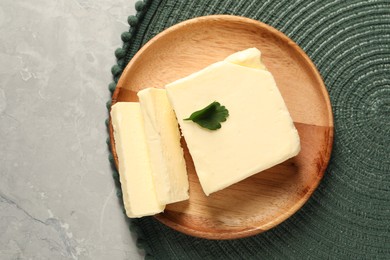 Cut tasty butter with parsley on grey table, top view