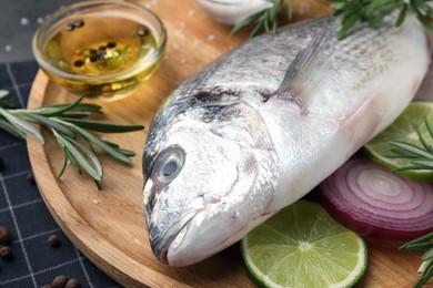 Photo of Fresh dorado fish and ingredients on wooden tray, closeup
