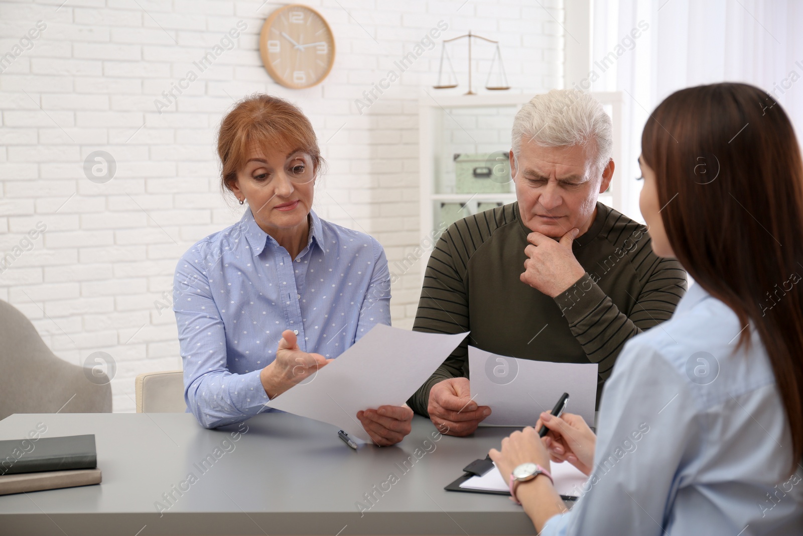 Photo of Young lawyer consulting senior couple in office