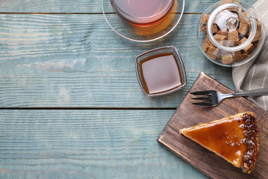 Photo of Piece of delicious cake with caramel served on blue wooden table, flat lay. Space for text