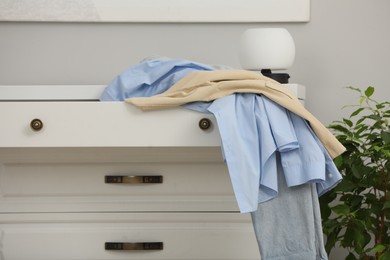 Photo of Set of clothes on white chest of drawers indoors