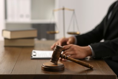 Photo of Law and justice. Closeup of judge at wooden table, focus on gavel in office