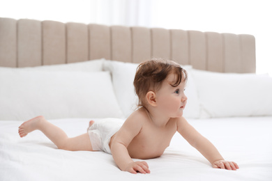 Photo of Cute little baby in diaper on bed