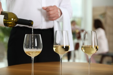 Waiter pouring wine into glass in restaurant, closeup