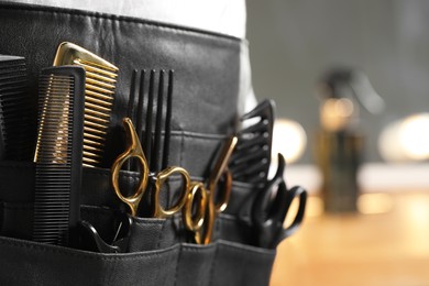 Hairstylist with professional tools in waist pouch in salon, closeup