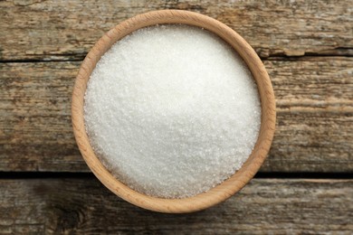 Photo of Granulated sugar in bowl on wooden table, top view