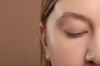 Photo of Woman with beautiful natural eyelashes on light brown background, closeup. Space for text