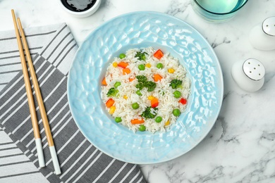 Photo of Boiled rice with vegetables served on marble table, flat lay