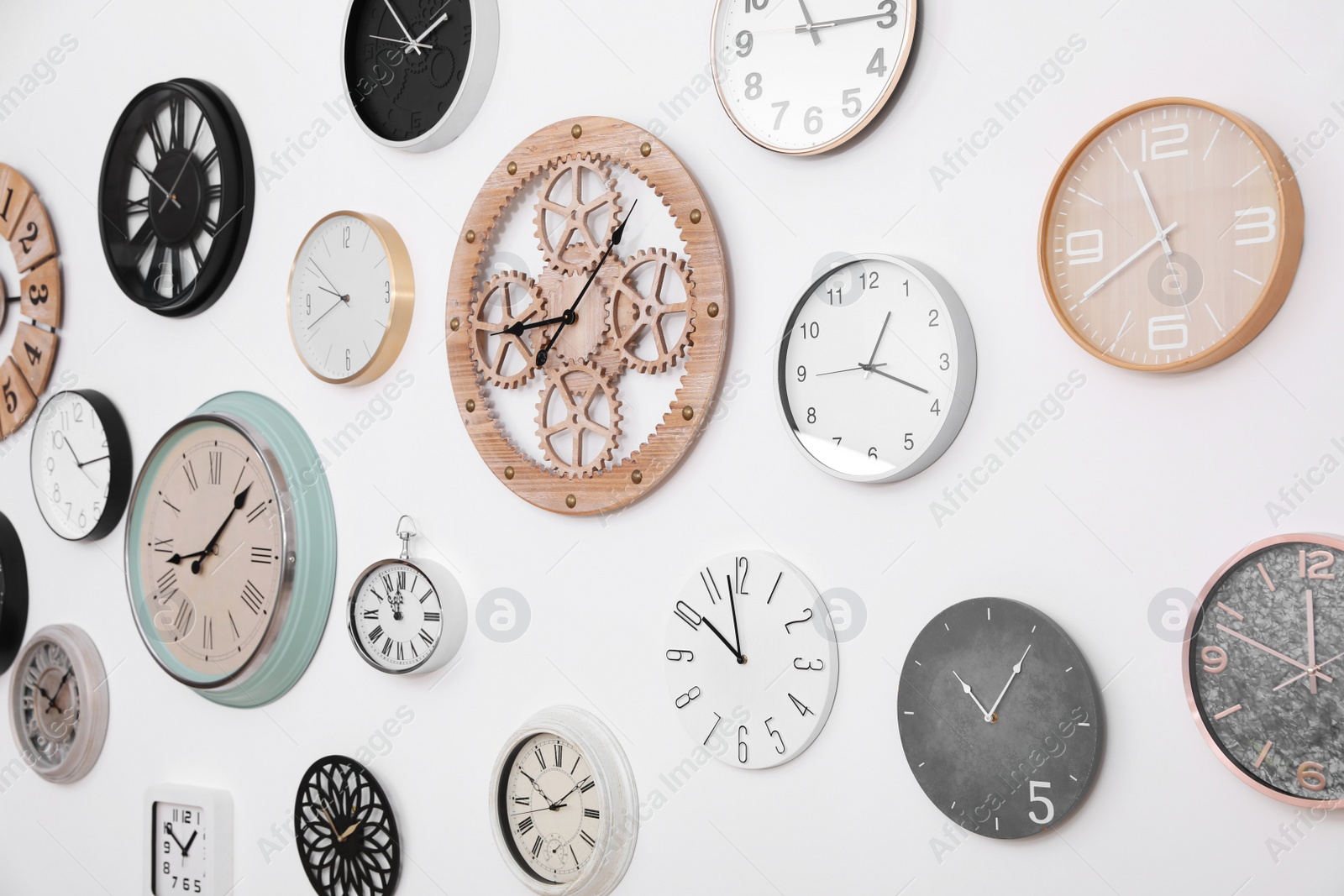 Photo of Collection of different clocks hanging on white wall