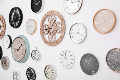 Photo of Collection of different clocks hanging on white wall