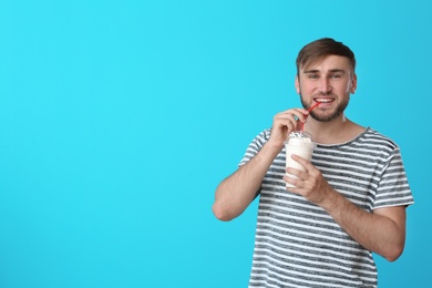 Photo of Young man with cup of delicious milk shake on color background