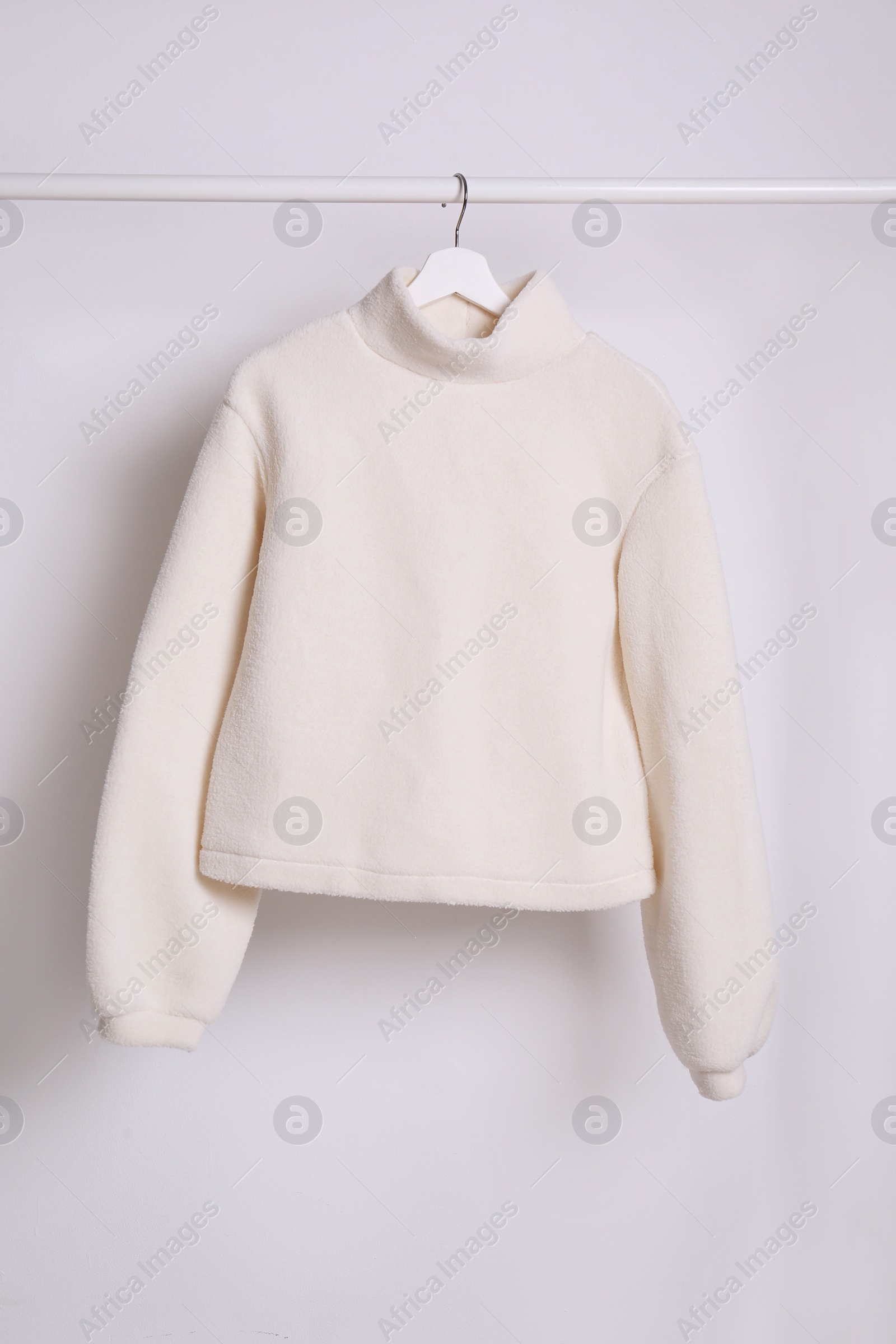 Photo of Warm sweater hanging on rack against white background