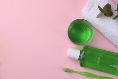 Photo of Flat lay composition with fresh mouthwash in bottle, glass and toothbrush on pink background. Space for text