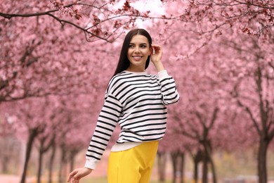 Pretty young woman in park with blooming trees. Spring look