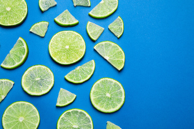 Photo of Juicy fresh lime slices on blue background, flat lay. Space for text