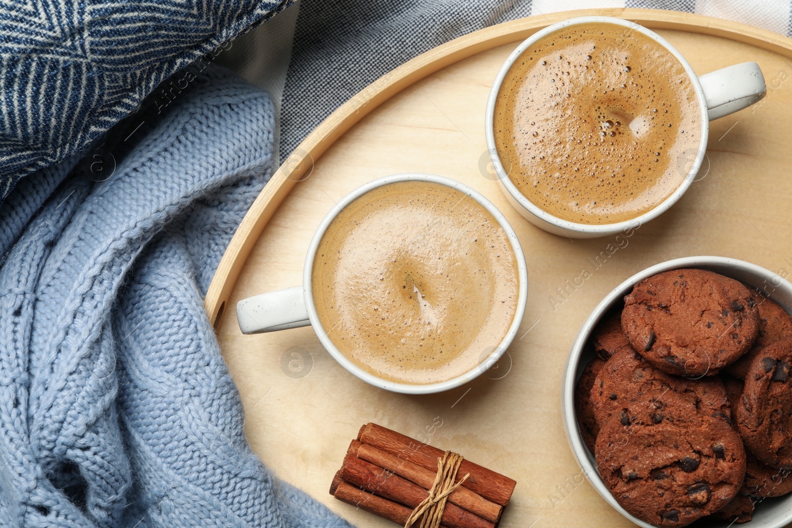 Photo of Cups of delicious hot coffee and cookies on fabric, flat lay. Winter drink