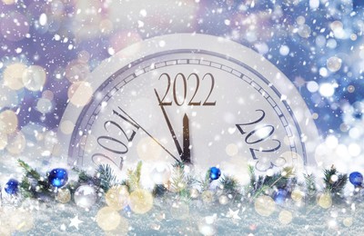 Clock counting last moments to New 2022 Year and beautiful fir branches with baubles. Bokeh effect