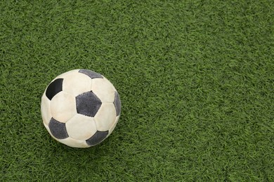 Photo of Dirty soccer ball on green football field, top view. Space for text