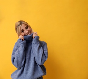 Happy woman in stylish sweater on yellow background. Space for text