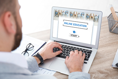 Man using laptop for online studying indoors, closeup. Adult education 